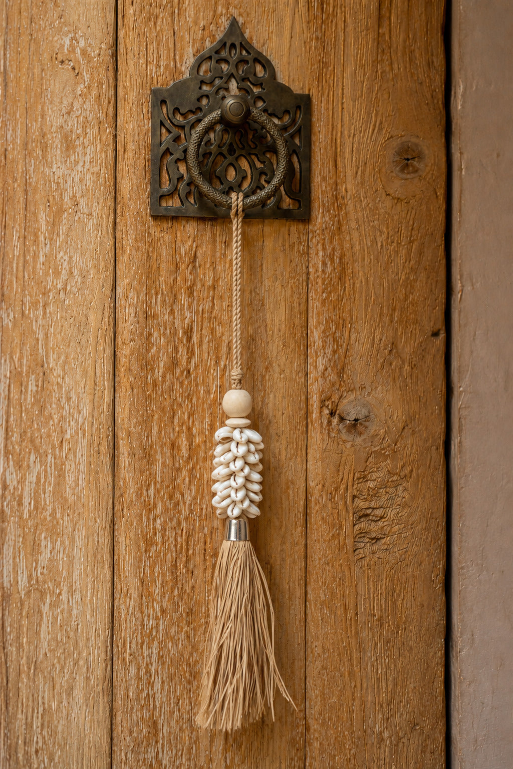 Pompon mural artisanal en coquillages cauris et raphia naturel
