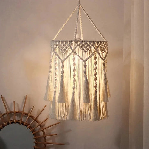 Abat-jour en macramé à franges suspendu éclairé dans une ambiance chaleureuse.