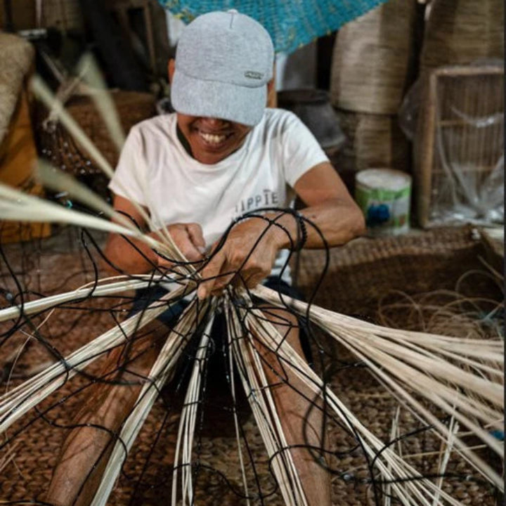 Artisan indonésien tressant à la main l'abat-jour en rotin Bali.