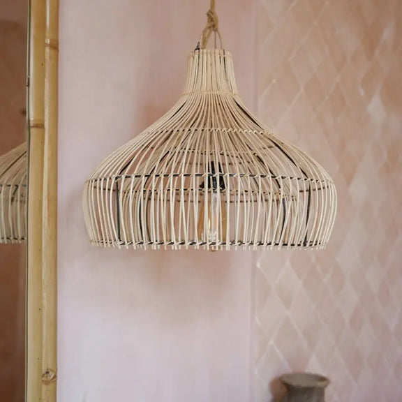 Abat-jour en rotin naturel suspendu dans une salle de bain avec une décoration bohème chic.
