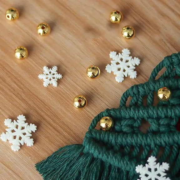 Flocons de neige blancs et boules dorées sur l'arbre de Noël en macramé