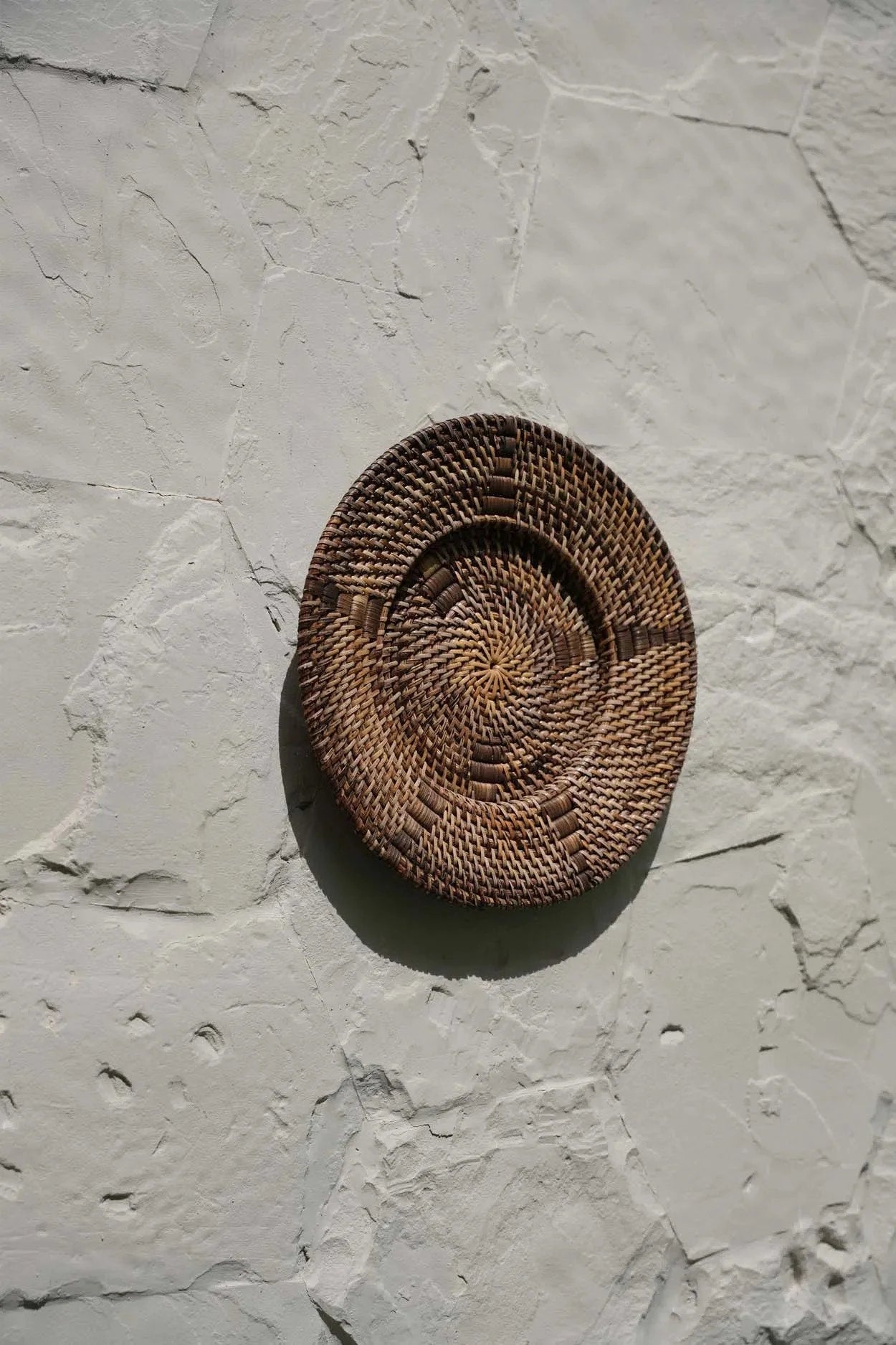 Assiette murale en rotin brun tressé avec motif en spirale au centre, diamètre 40 cm