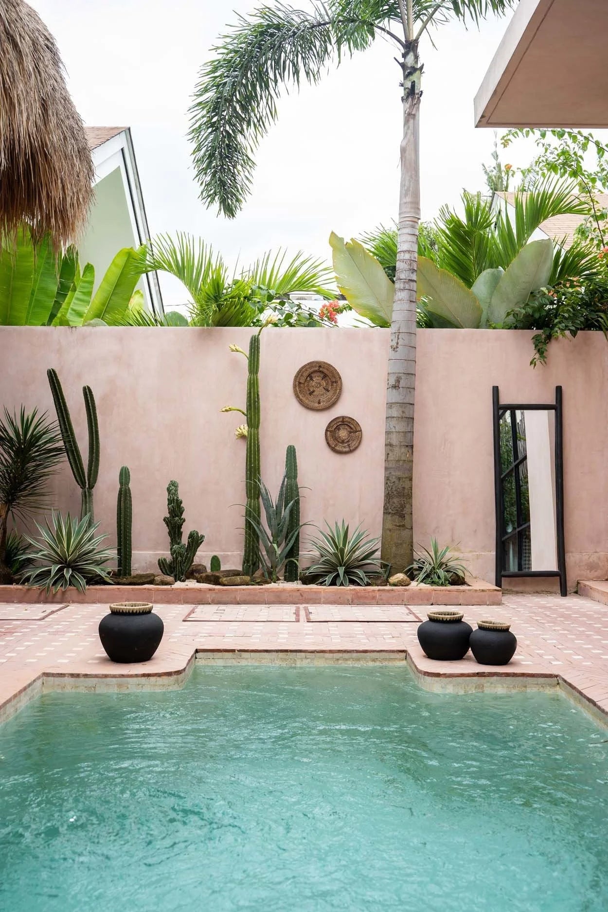 Piscine rectangulaire avec forme irrégulière, entourée de carreaux clairs et pots décoratifs