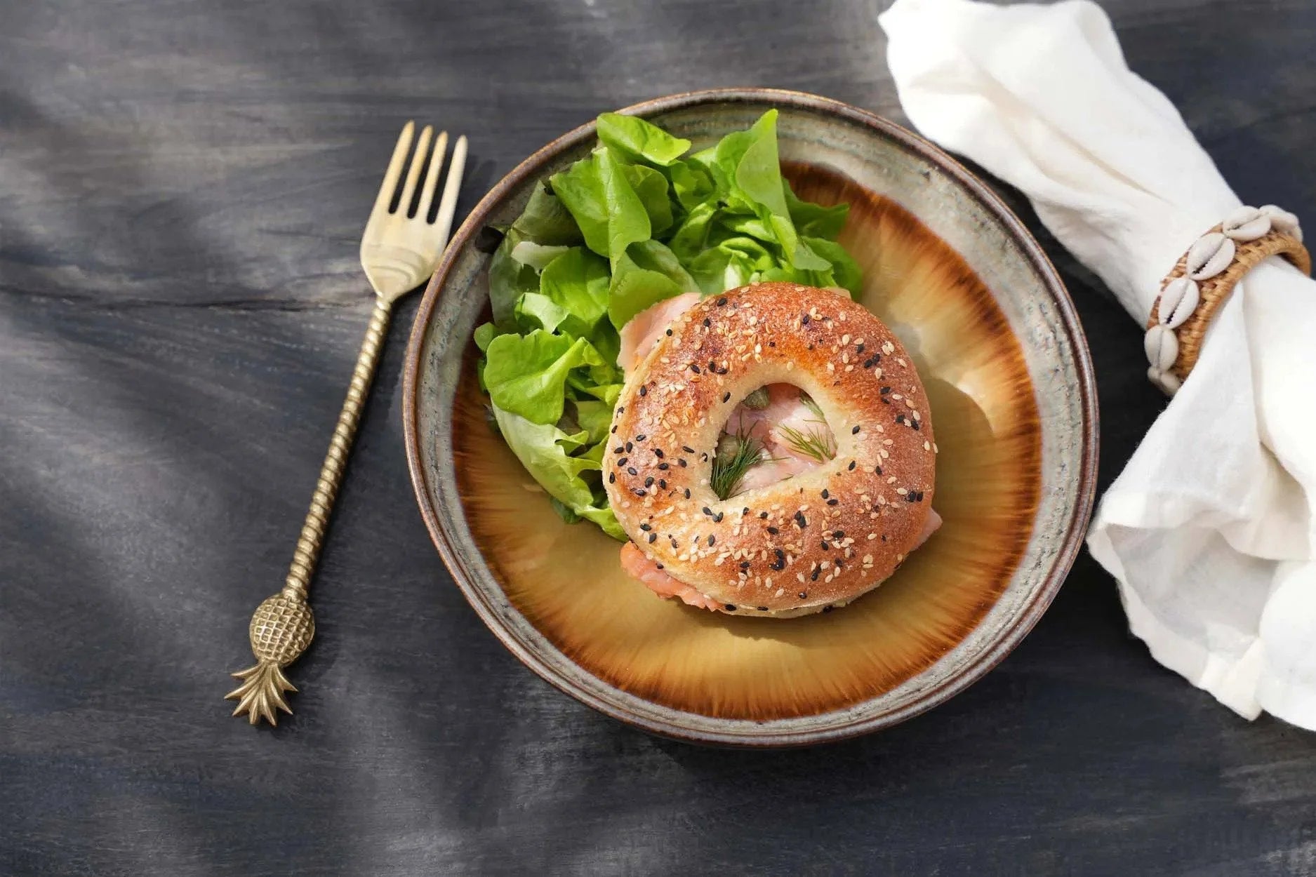 Sandwich au bagel avec des greens sur une assiette à pâtes en céramique grise