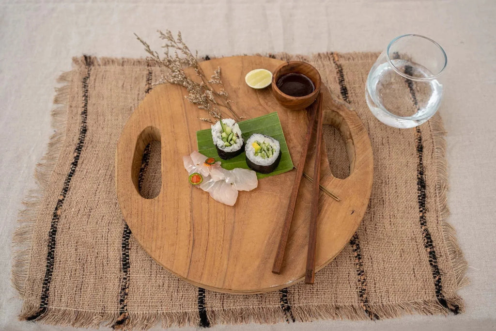 Sushi rolls avec sashimi et sauce d’accompagnement sur un bol en bois de teck naturel rond