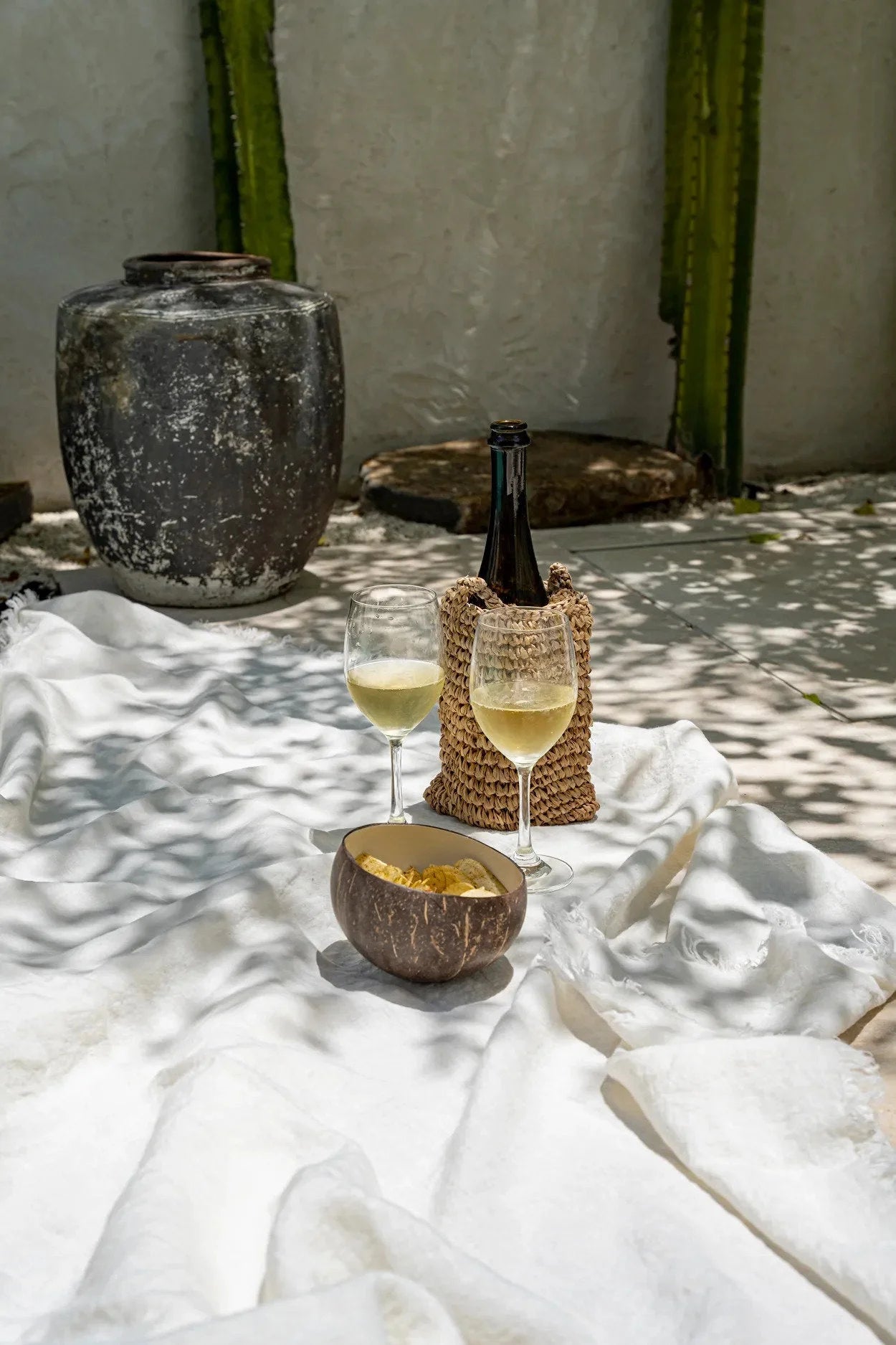 Deux verres de vin blanc et une bouteille dans un porte-canneau en osier