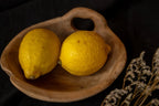 Deux citrons jaunes mûrs dans un bol en bois de teck avec poignée intégrée naturelle