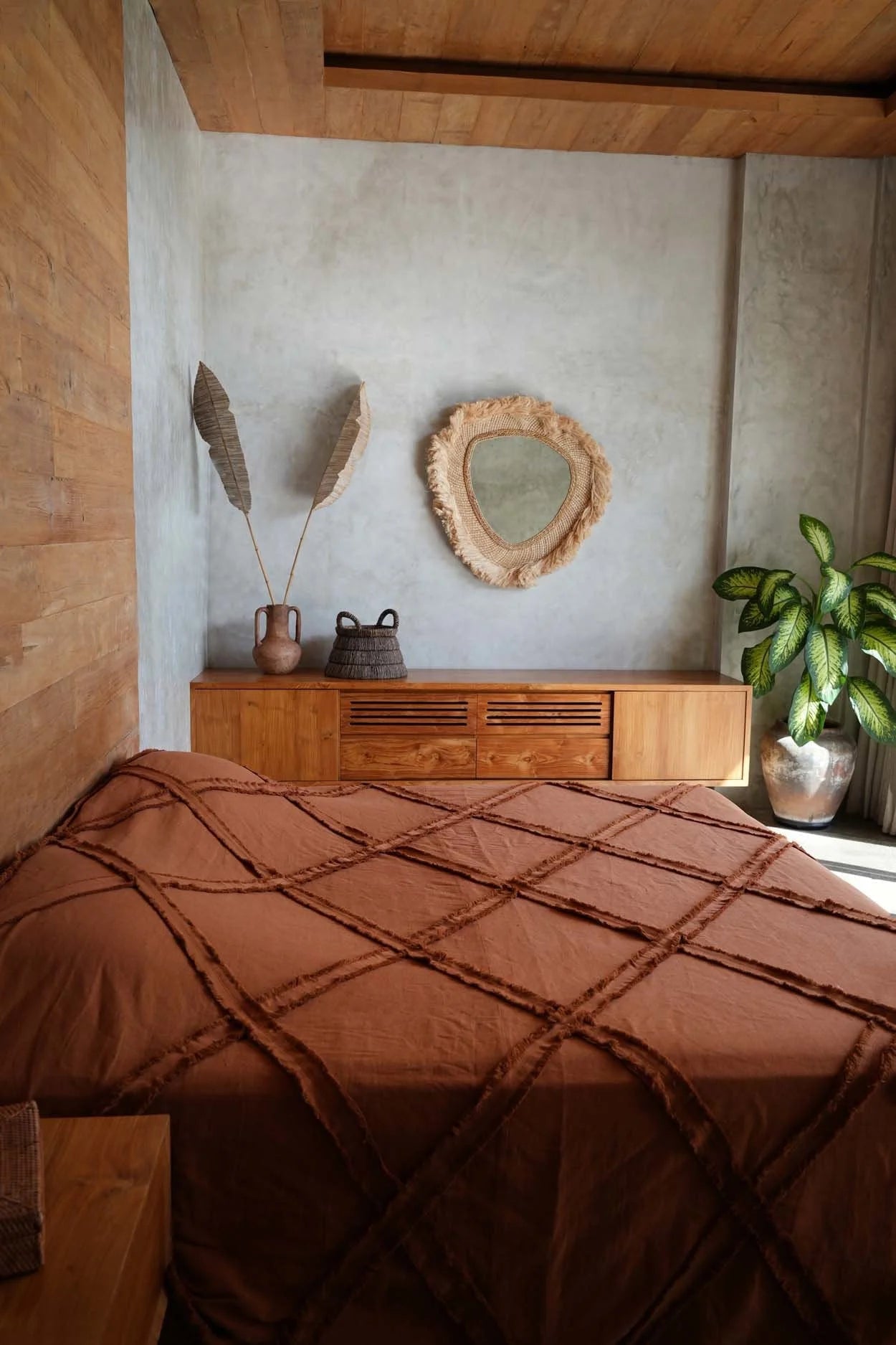 Couvre-lit en coton terracotta avec losanges et franges macramé dans une chambre rustique