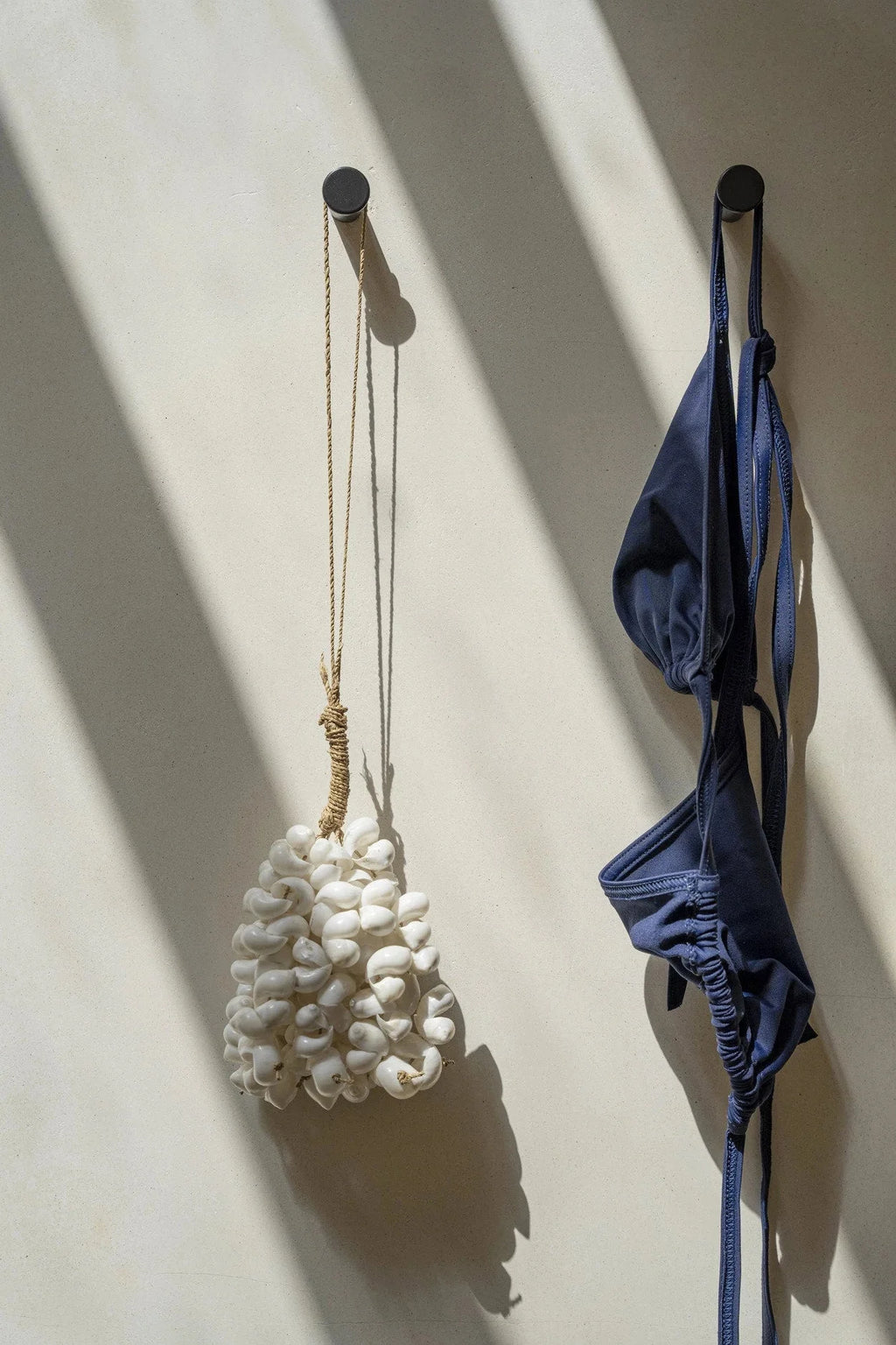 Maillot de bain deux pièces bleu marine suspendu sur un crochet mural en coquillages blancs