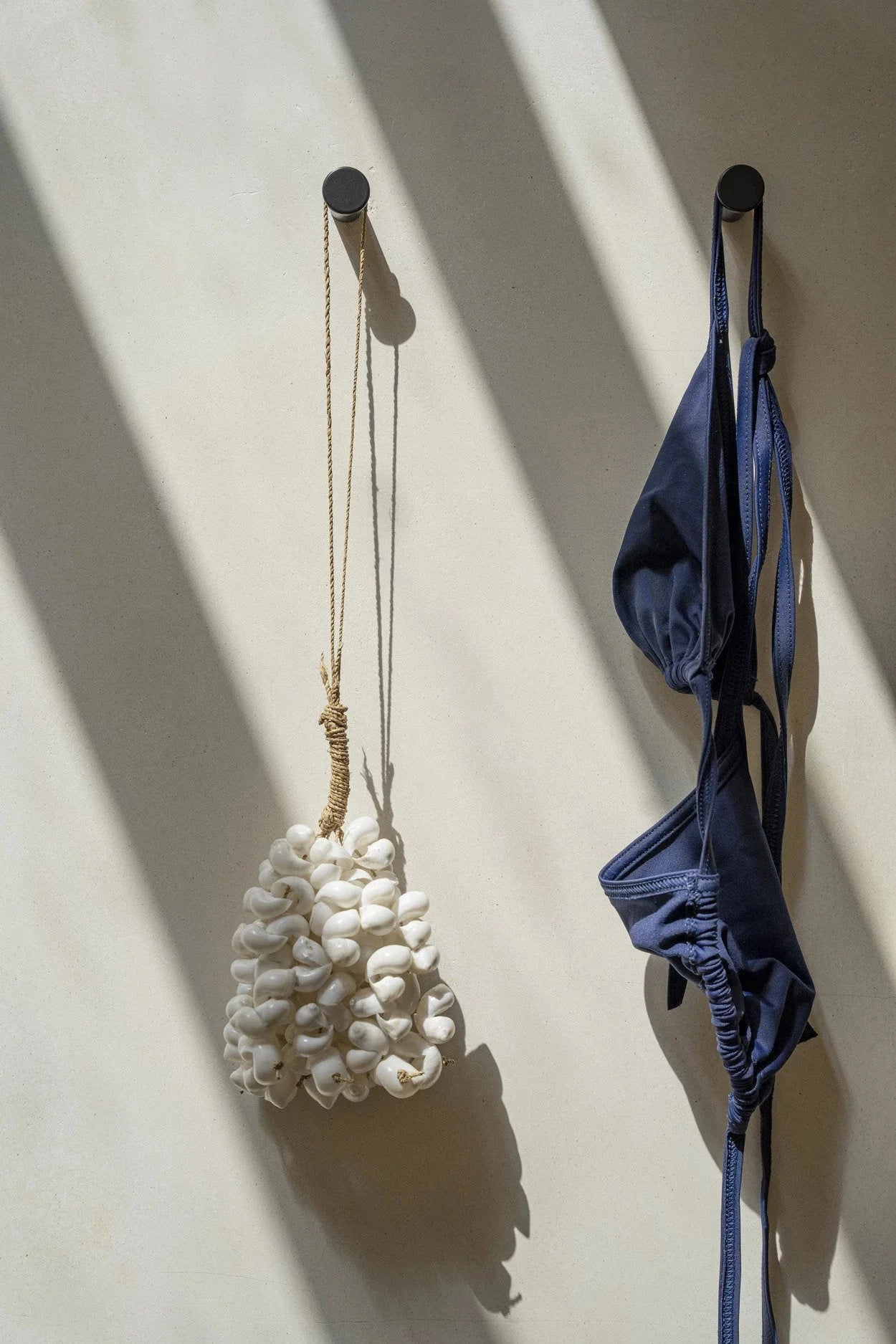 Maillot de bain deux pièces bleu marine suspendu sur un crochet mural en coquillages blancs