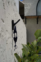 Bikini noir en crochet suspendu sur un crochet mural dans la pièce design Teck Noir