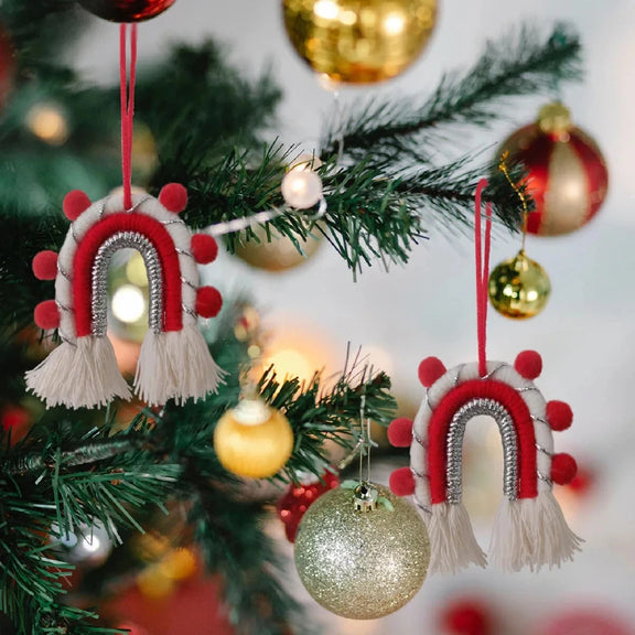 Décoration de Noël arche bohème en macramé, ornée de pompons rouges et dorés, idéale pour sublimer votre sapin avec une touche bohème chic.