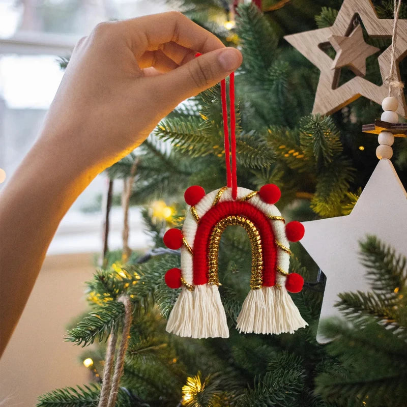 Décoration de Noël arche bohème en macramé rouge et blanc, avec pompons rouges et dorés et franges blanches, pour un style festif et raffiné.