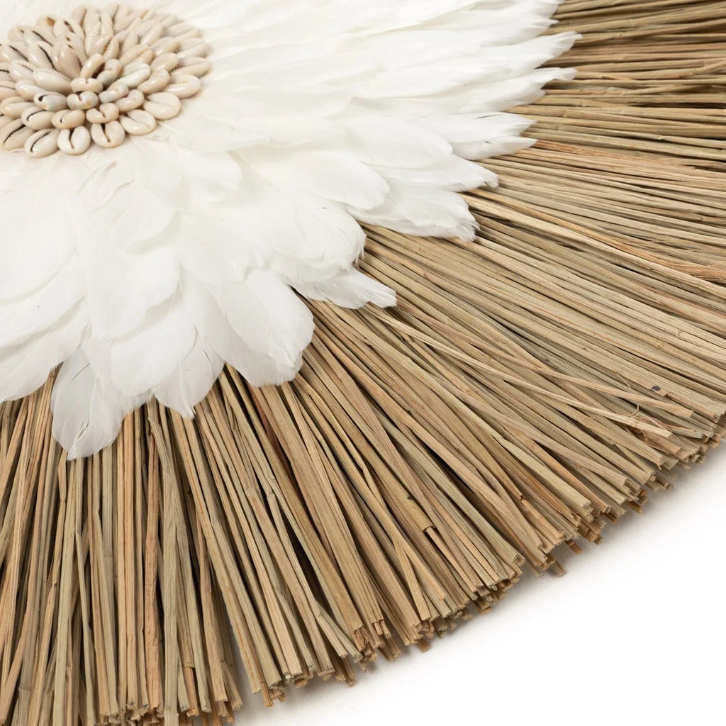 Décoration murale ronde en plumes blanches et coquillages naturels sur un mur