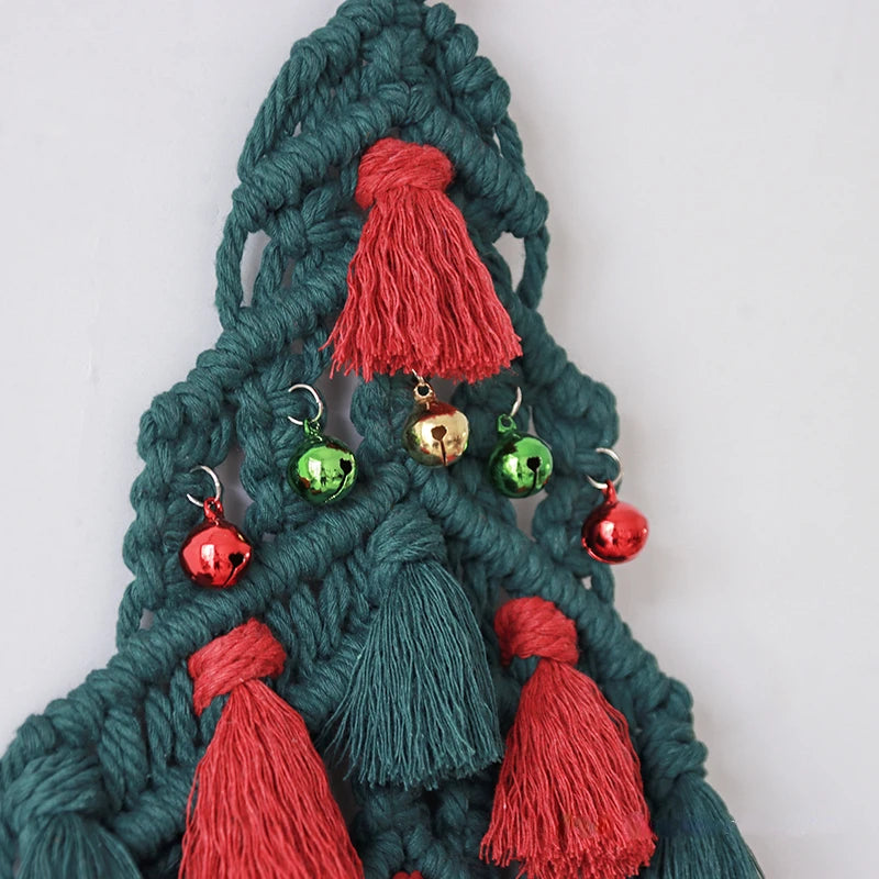 Gros plan sur les détails d’un sapin de Noël en macramé, avec pompons rouges et clochettes dorées.