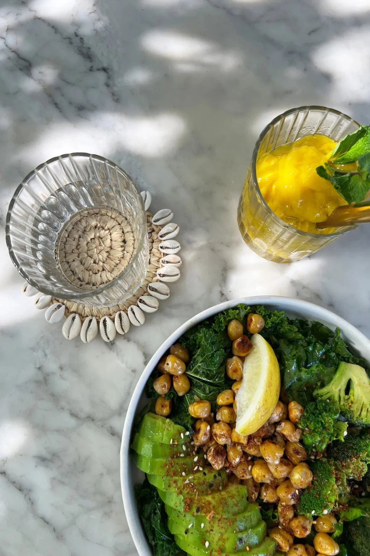Saladier vert avec avocat, maïs, citron et deux verres, dont un avec boisson jaune