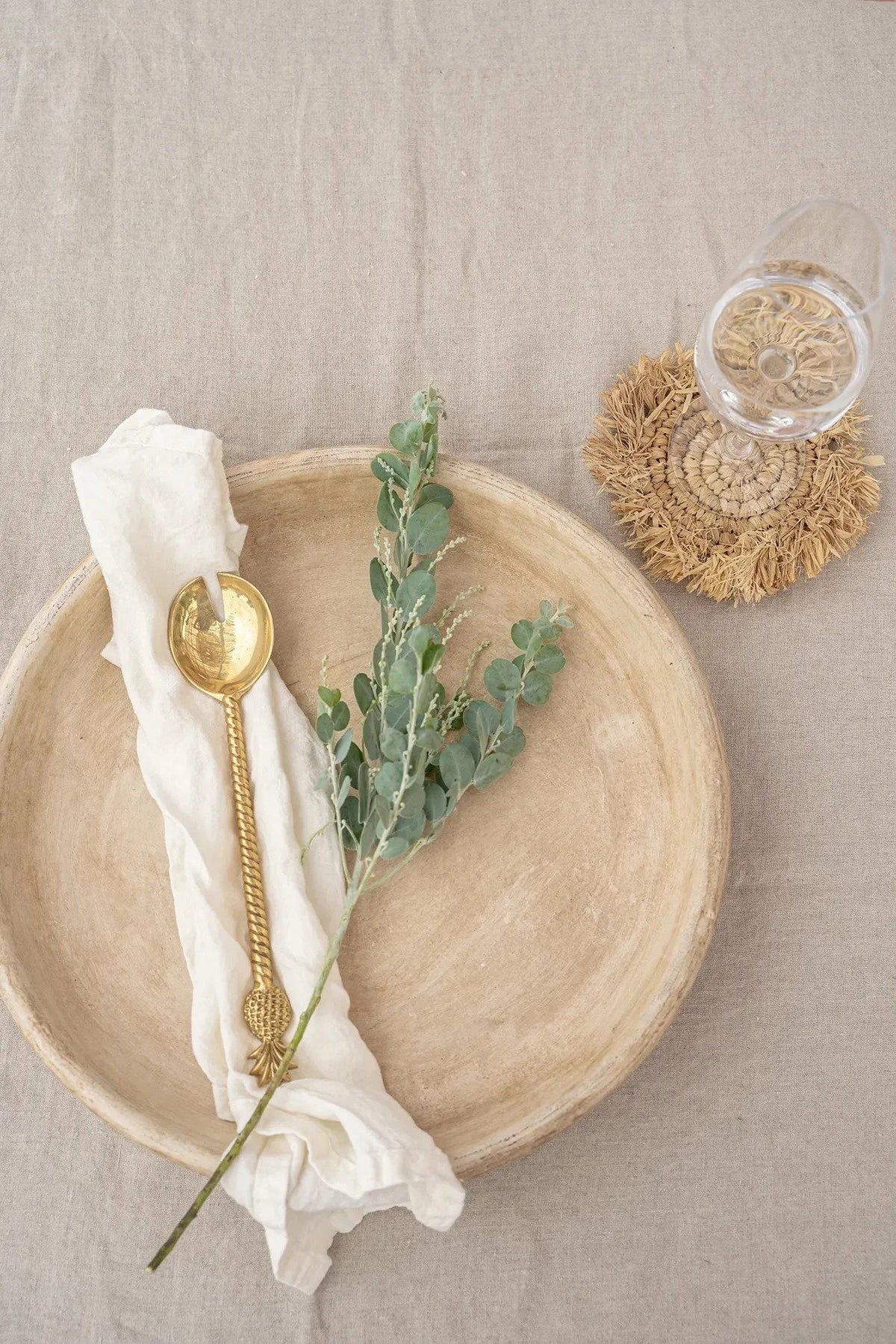 Assiette céramique beige avec cuillère dorée et branche d’eucalyptus verte