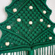 Franges et perles en bois du sapin en macramé vert, décoration murale pour Noël.