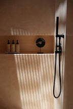 Système de douche noir moderne avec tête de douche à main sur un socle en marbre noir