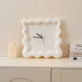 Horloge ondulée blanche posée sur un meuble, décoration minimaliste.