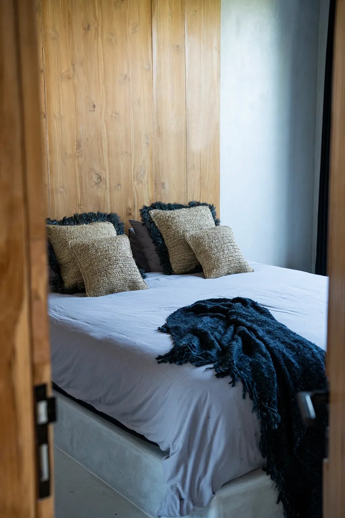 Housse de coussin carrée en raphia naturel tressé sur un lit avec oreillers décoratifs