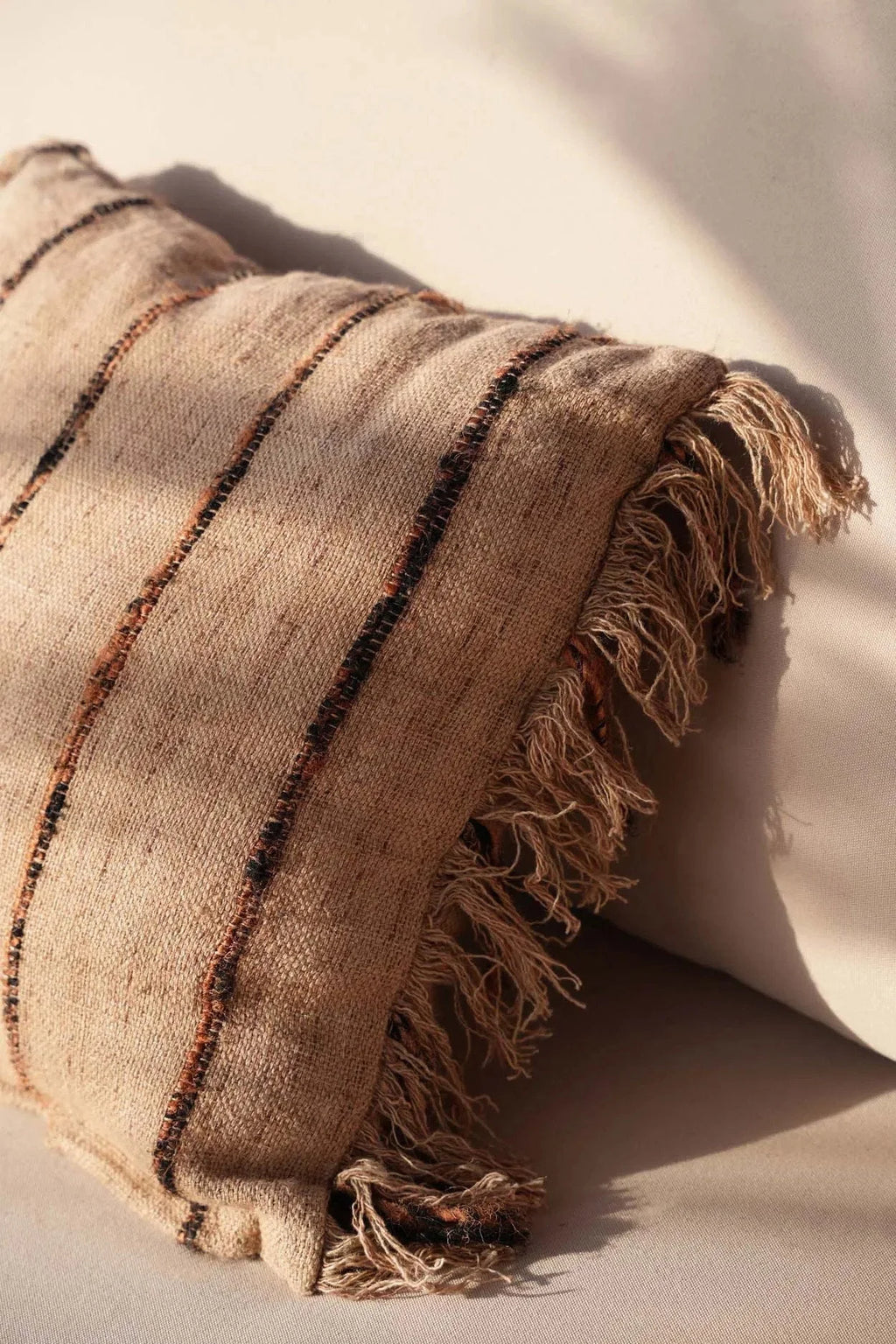 Housse de coussin en coton beige avec rayures marron foncé et bords effilochés