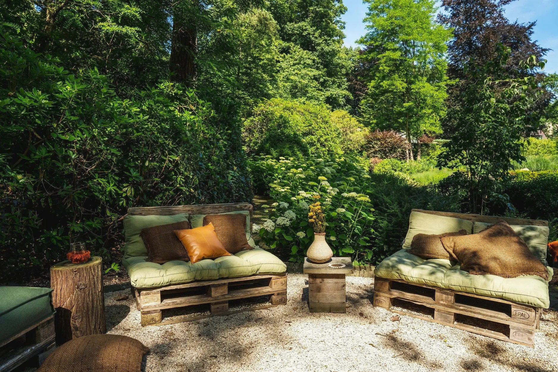 Espace extérieur avec mobilier en palettes en bois, coussins verts et coussins marron 60x60 cm