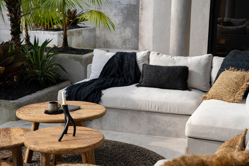 Housse de coussin noire en coton avec franges sur un canapé d’extérieur blanc