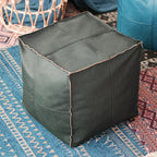 Housse de pouf marocain en forme de cube, couleur noire, posée sur un tapis bohème.