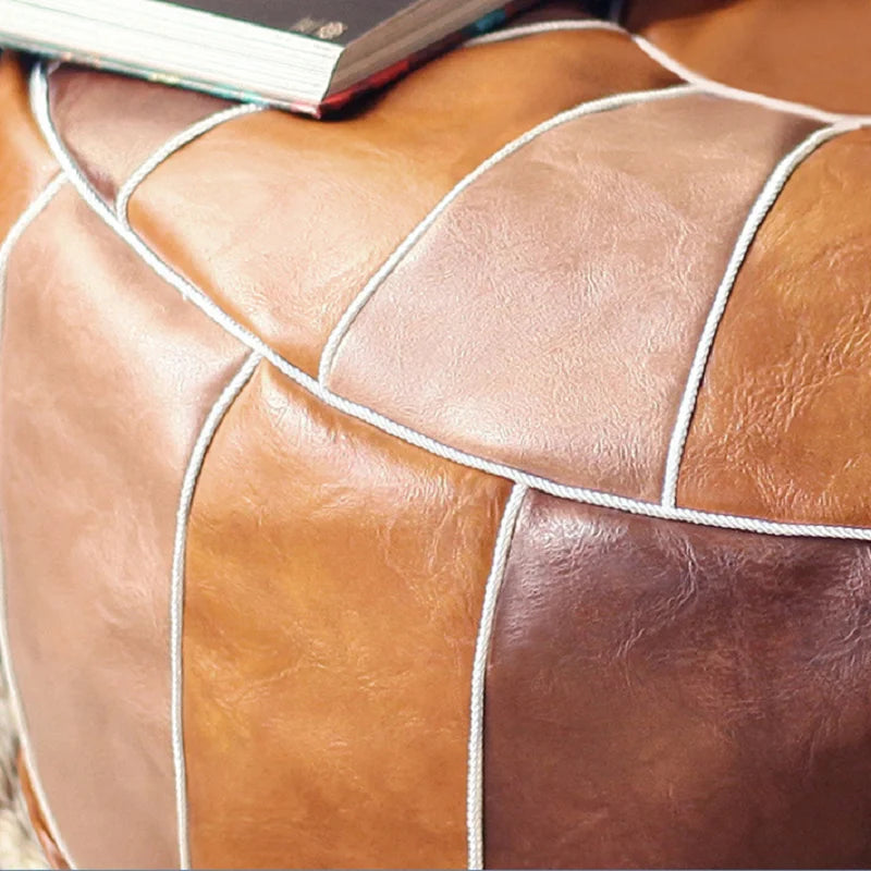 Gros plan sur une housse de pouf marocain en cuir synthétique marron avec coutures décoratives.