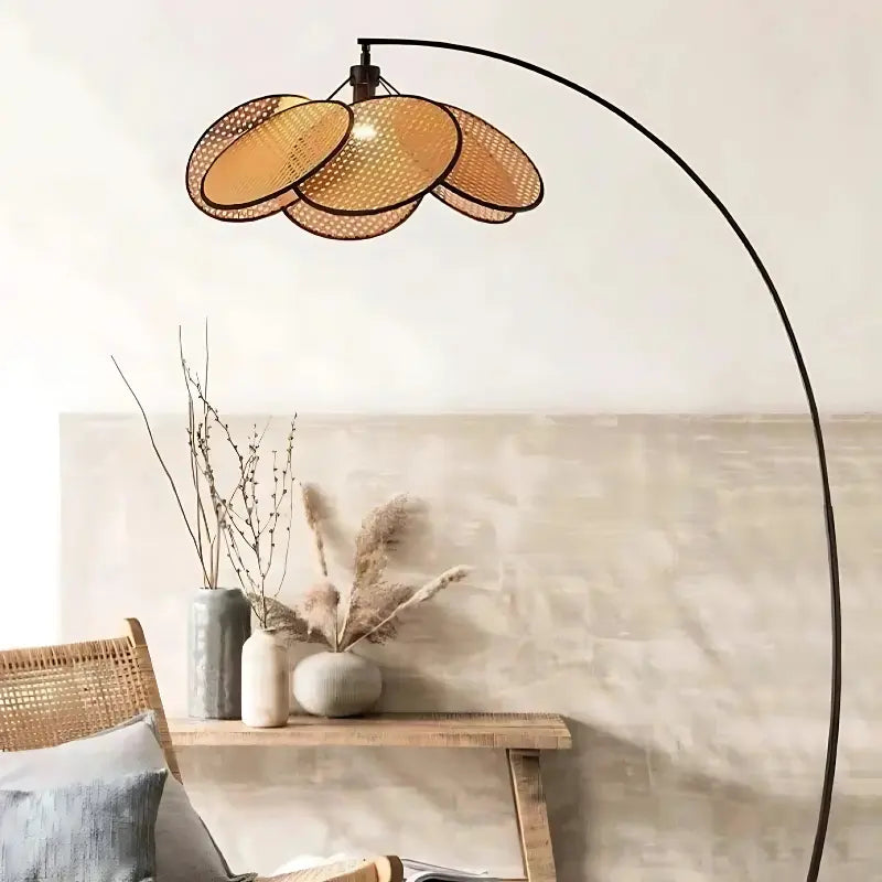 Lampadaire avec abat-jour en rotin dans un salon bohème avec fauteuil tressé et table en bois.