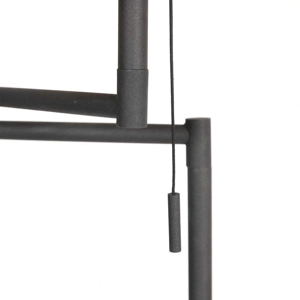 Interrupteur à chaîne en métal gris foncé sur un lampadaire noir avec abat-jour doré