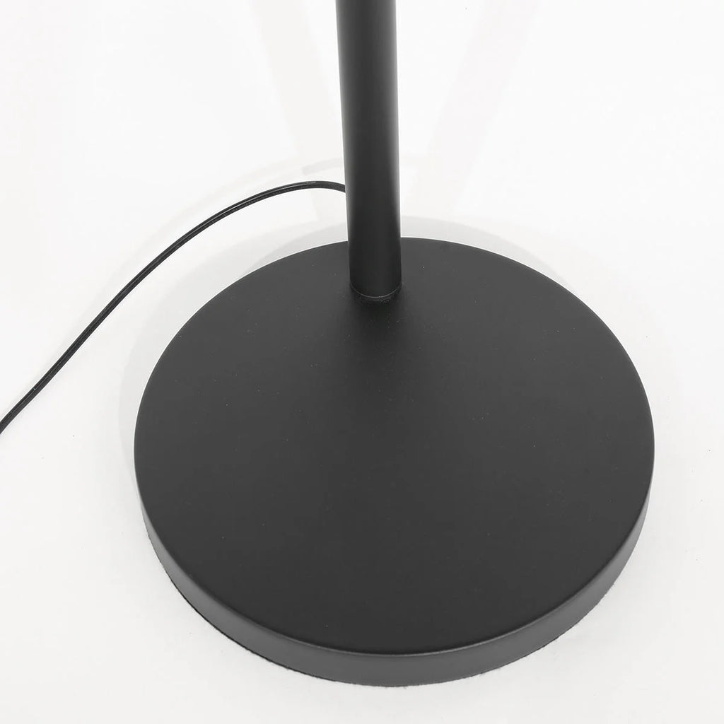 Base circulaire noire mate avec tige cylindrique, lampe en rotin tressé noir et beige sur arches métal noir H180 cm