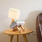 Lampe de chevet bonhomme en bois posée sur une table de chevet à côté d'un canapé