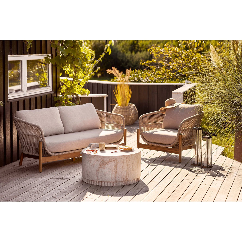 Canapé en osier beige rembourré avec pieds en bois et fauteuil assorti sur terrasse en bois