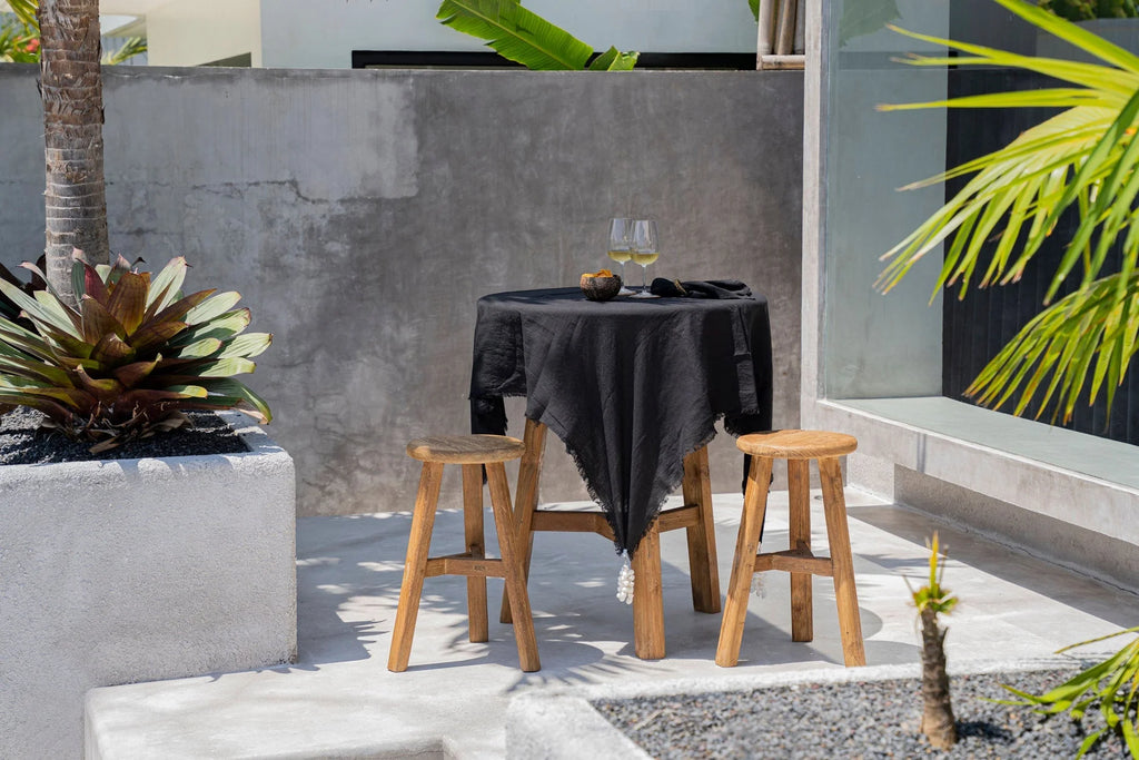 Nappe en lin noir 150x200 cm sur une table ronde extérieure avec deux tabourets en bois