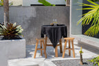 Nappe en lin noir 150x200 cm sur une table ronde extérieure avec deux tabourets en bois