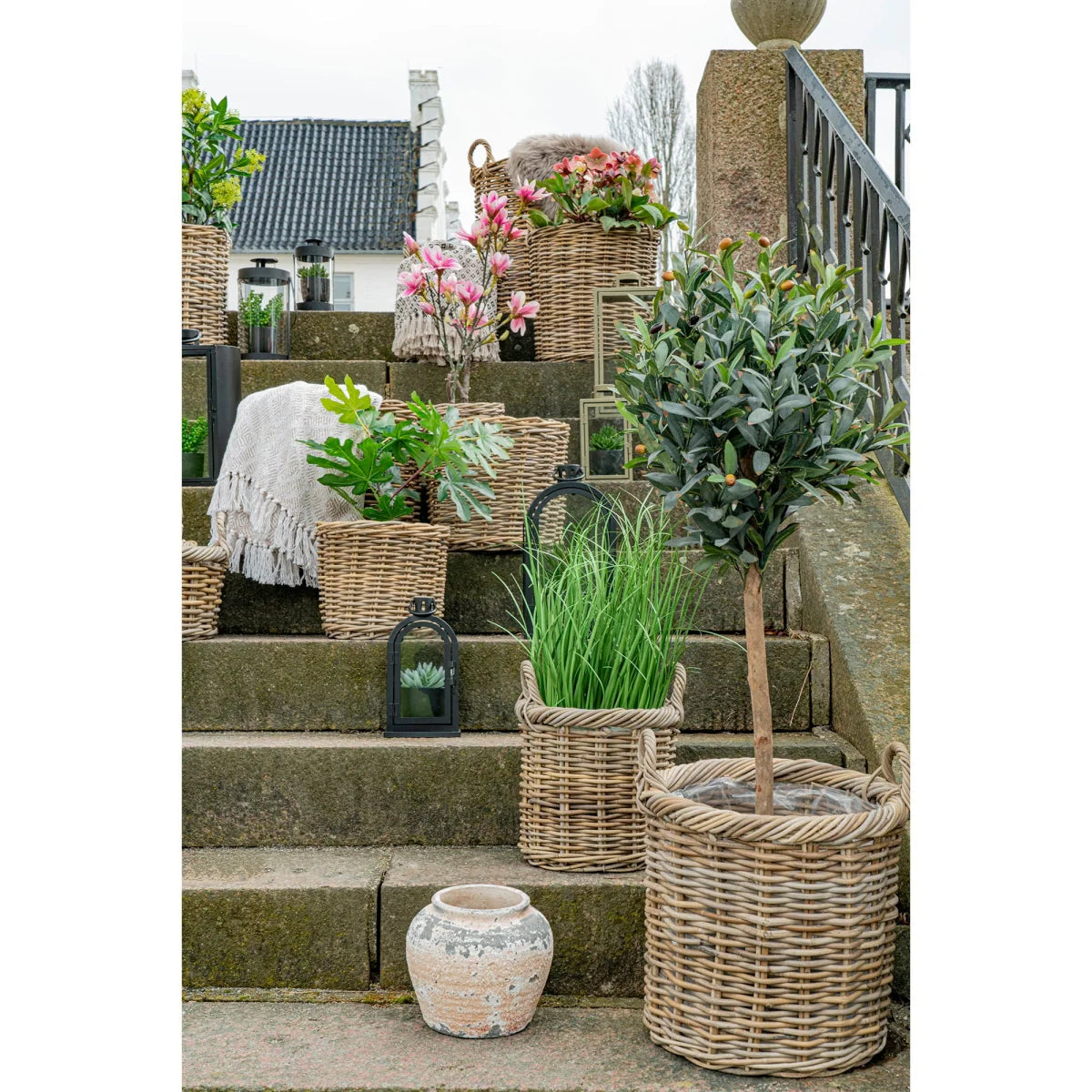 Panier rond en rotin tressé gris avec arbre élancé planté dedans