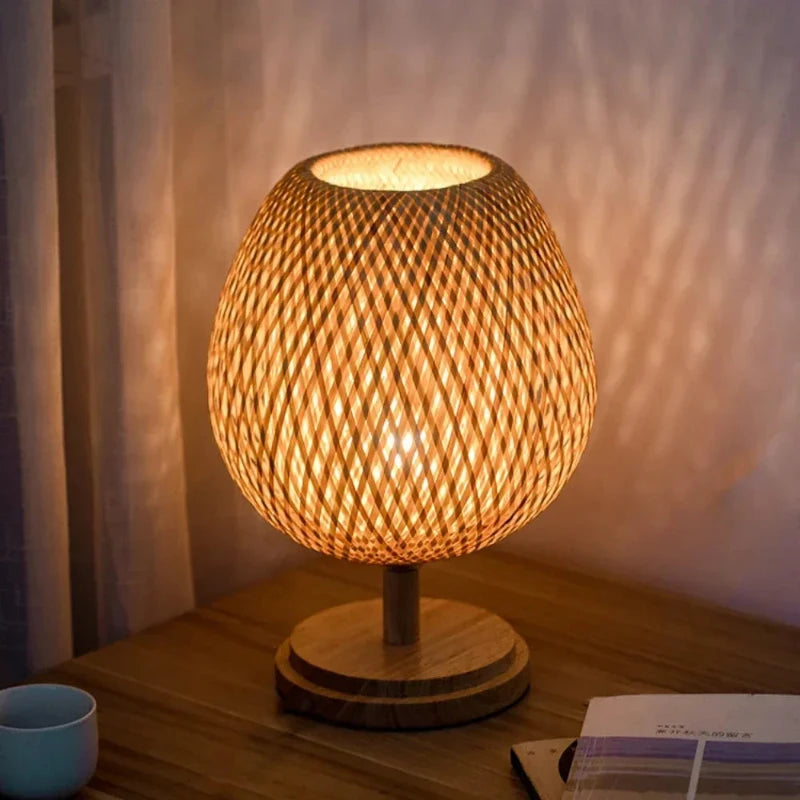 Petite lampe rotin allumée sur une table en bois avec lumière tamisée