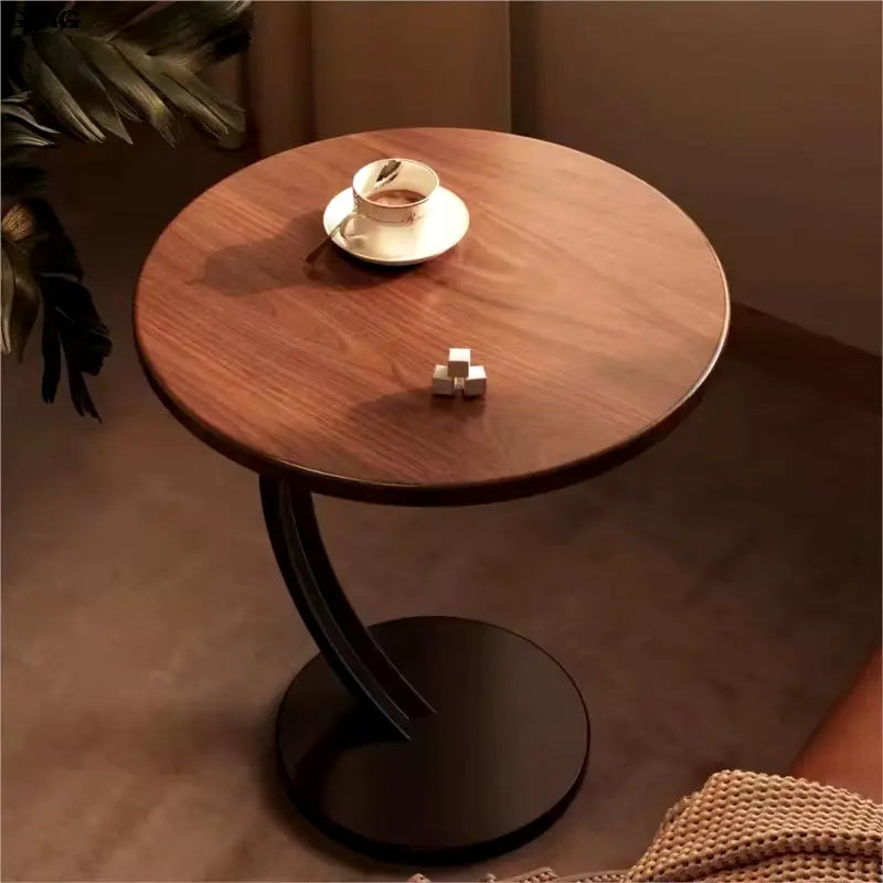 Petite table de salon ronde en bois et métal noir, mise en situation près d'un canapé.