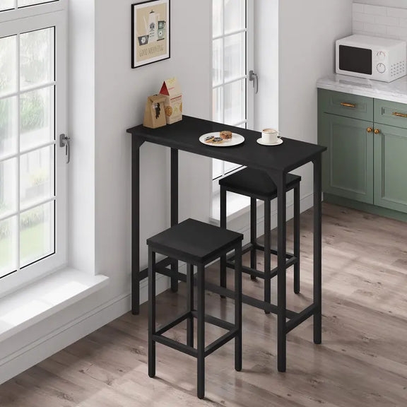 Petite table haute à manger noire installée dans une cuisine lumineuse avec accessoires de décoration.