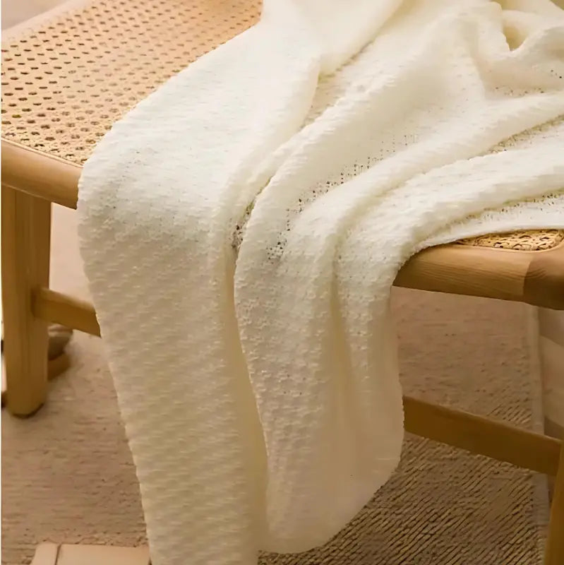 Plaid blanc en maille gaufrée sur une chaise en bois