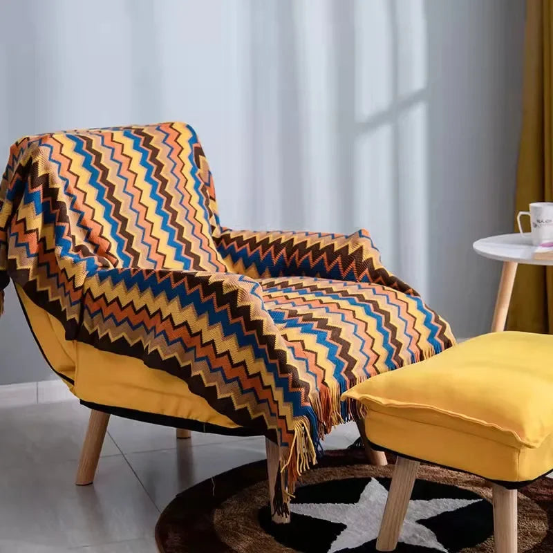 Couverture en plaid chevron coloré sur fauteuil jaune, parfaite pour des moments cocooning