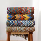 Piles de plaids chevron colorés sur un tabouret en bois pour des moments cocooning