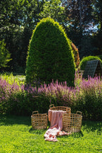 Trois paniers en rotin avec une couverture rose saumon dans un jardin coloré
