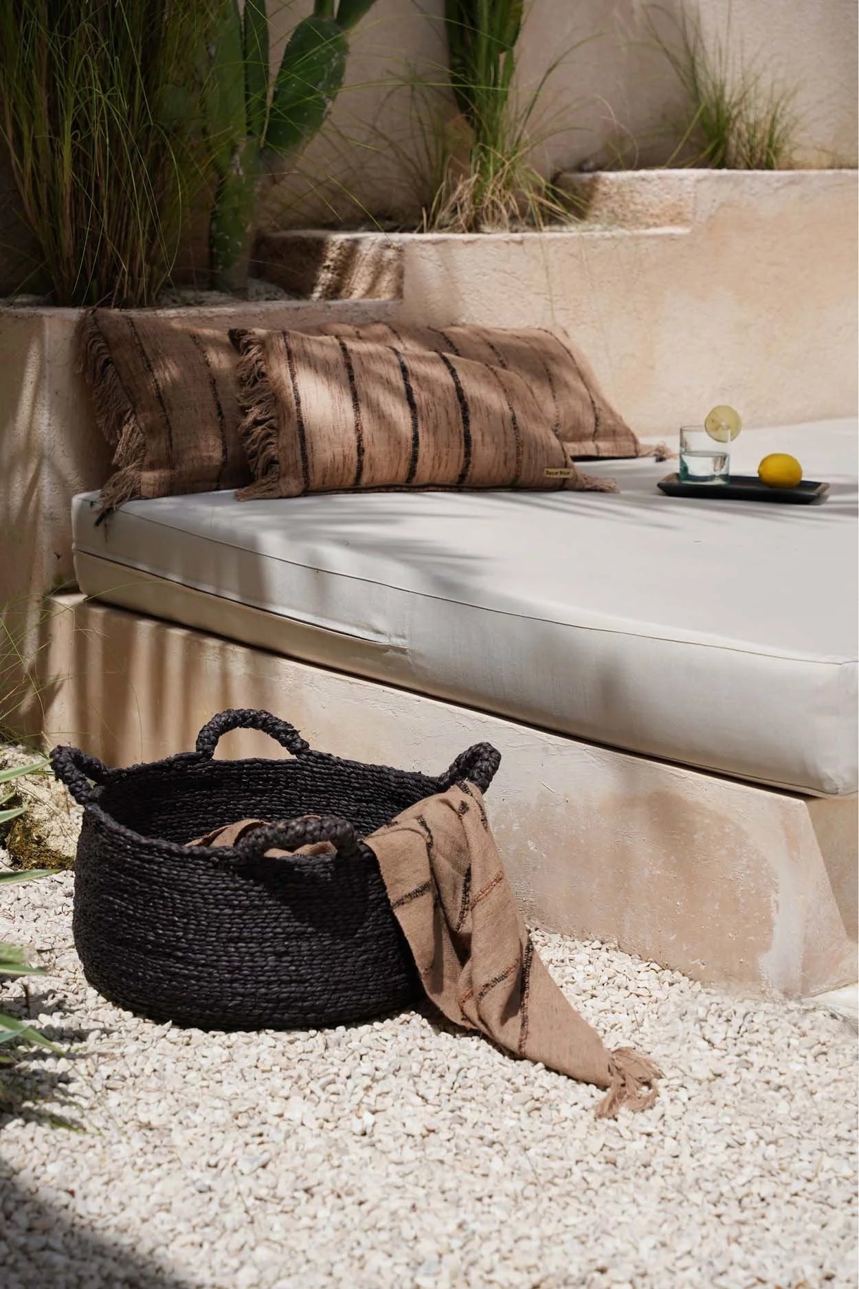Panier en tissage noir avec poignées et couverture beige rayée à franges pour canapé ou lit