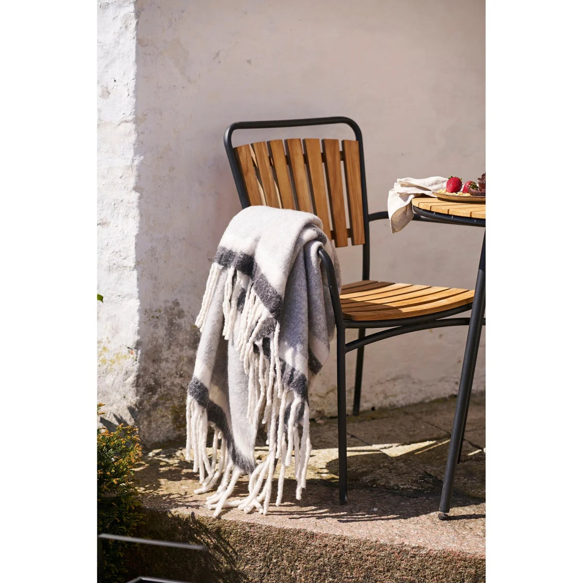 Plaid duveteux crème à rayures gris-blanc avec franges longues sur chaise en bois