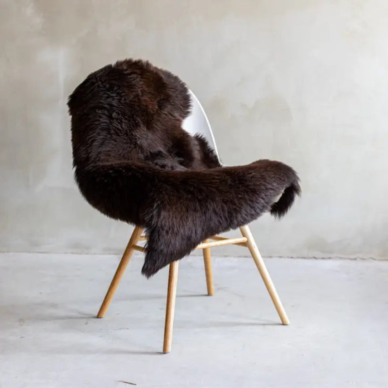 Plaid peau de mouton marron sur une chaise, parfait pour une décoration chaleureuse et cocooning.