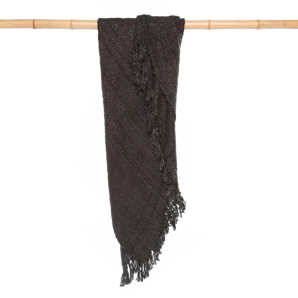 Plaid rectangulaire en coton tissé noir avec franges, drapé sur une barre en Bambou