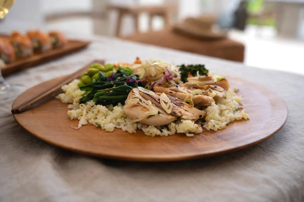 Bol de poulet grillé et légumes avec riz dans un plateau rond en racine de teck naturel